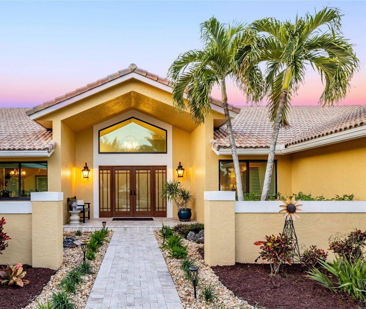 Twilight entrance of a Carter Collective listing in Davie, Florida, framed by royal palms