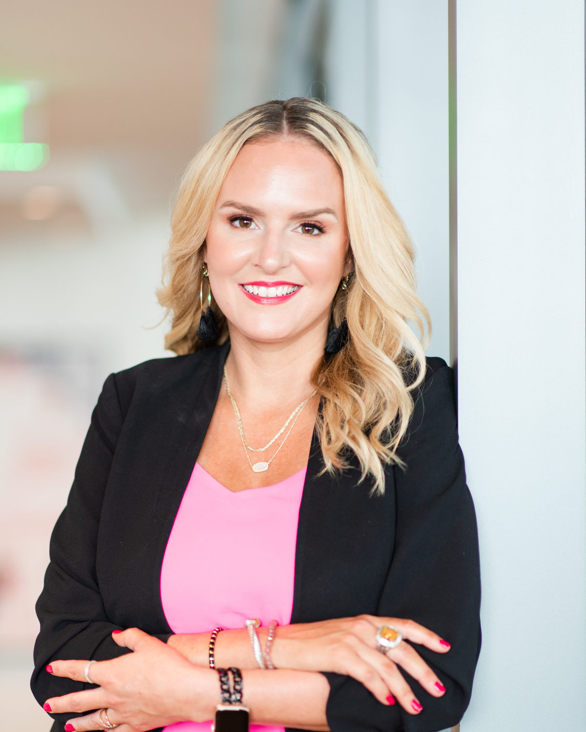 Tara Carter in a black blazer and pink top, arms crossed, smiling